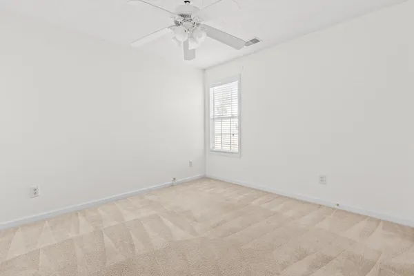 an empty room with windows and chandelier fan