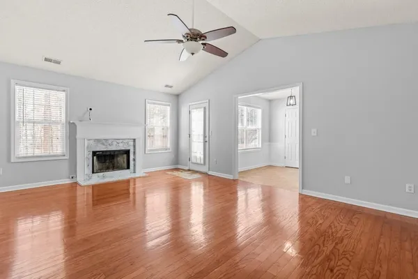 a view of an empty room with window and wooden floor