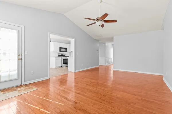 a view of empty room with wooden floor and ceiling fan
