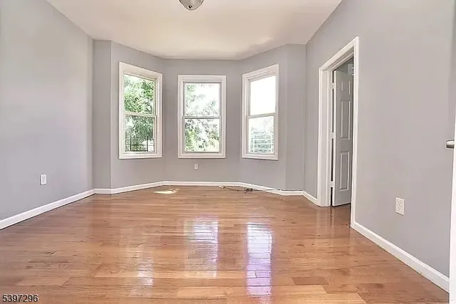 a view of an empty room with a window and wooden floor