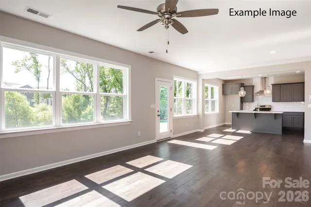 a view of an empty room with kitchen view and a window