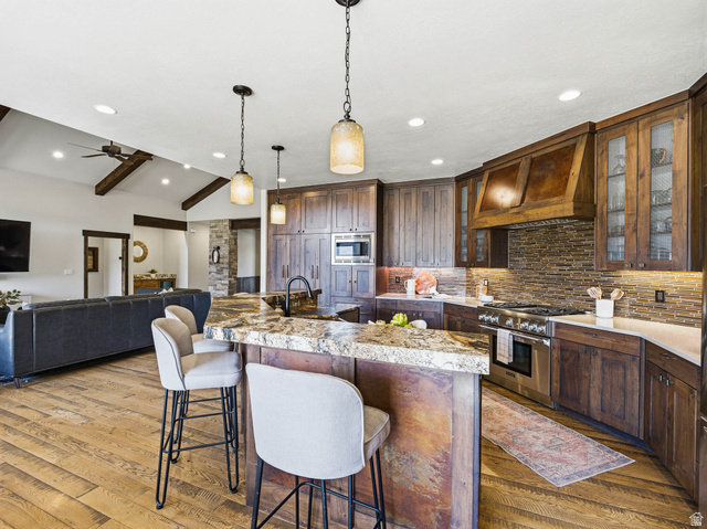 402 Shadow Hill Road Wanship, UT 84017 - Photo 14 of 90 Kitchen featuring a breakfast bar area, lofted ceiling with beams, stainless steel appliances, decorative light fixtures, and decorative backsplash