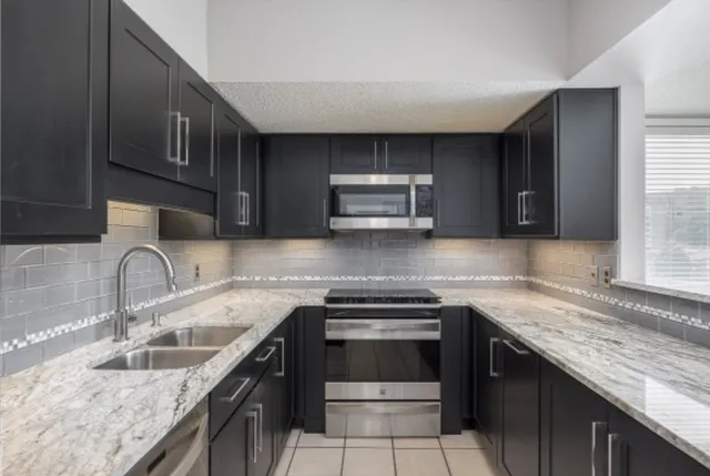 a kitchen with granite countertop a sink and stove top oven