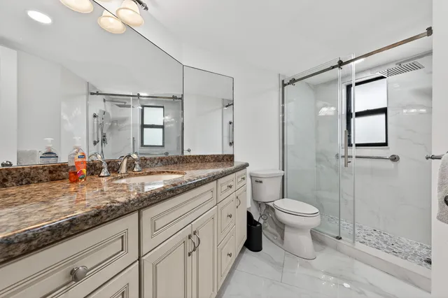 a bathroom with a granite countertop shower a toilet and sink