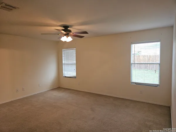 an empty room with windows and fan