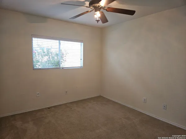 an empty room with a window and a fan