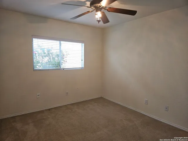 an empty room with a window and a fan