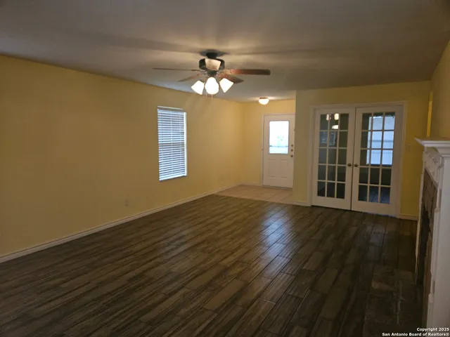 a view of an empty room with wooden floor and a window