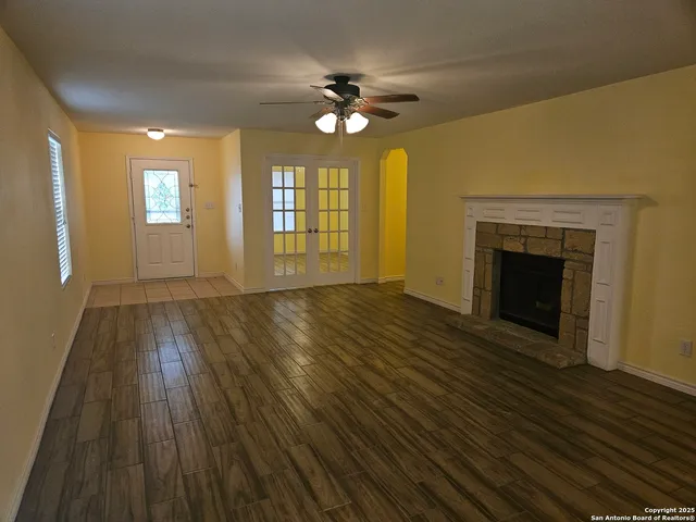 a view of an empty room with wooden floor and a fireplace