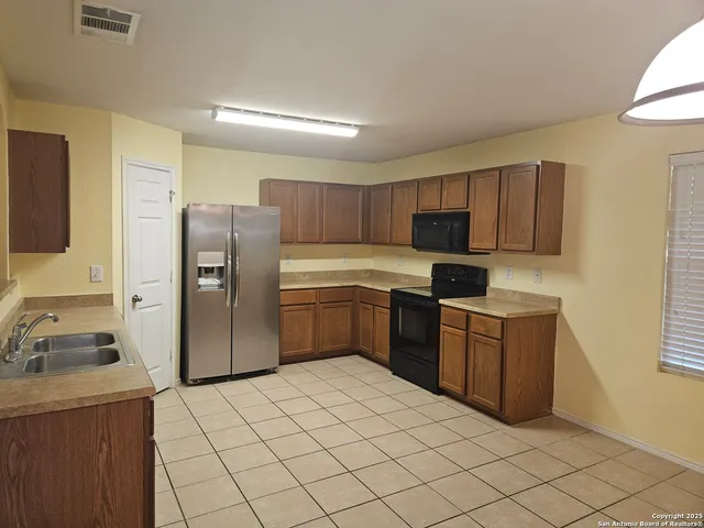 a kitchen with granite countertop a refrigerator sink and wooden cabinets