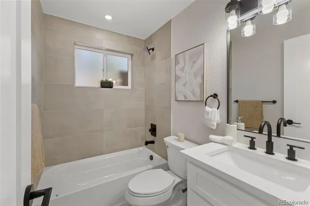 a bathroom with a toilet a sink a mirror a bathtub and vanity