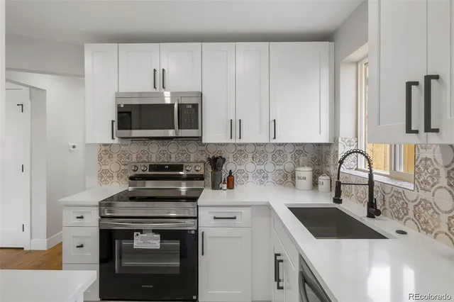 a kitchen with granite countertop white cabinets sink and stainless steel appliances