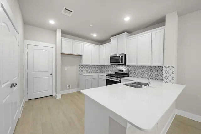 a kitchen with white cabinets and stainless steel appliances