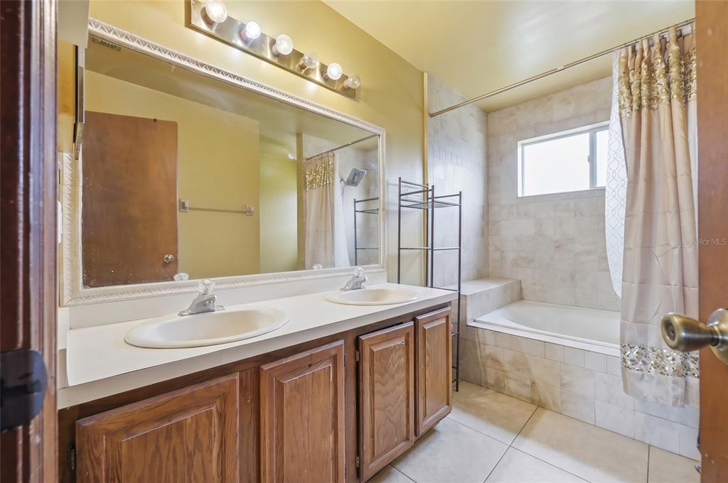 3027 Queens Gate Road Orlando, FL 32818 - Photo 29 of 34 a bathroom with a sink double vanity mirror and a bathtub
