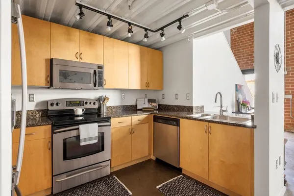 a kitchen with stainless steel appliances granite countertop a stove a sink and a microwave