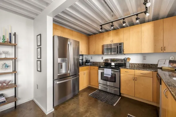 a kitchen with stainless steel appliances granite countertop a refrigerator and a stove top oven