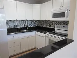 a kitchen with white cabinets and sink