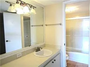 a bathroom with a granite countertop shower sink and mirror