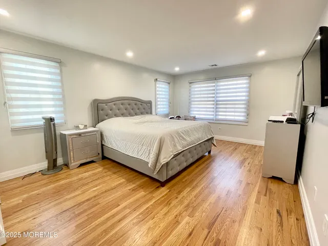 a spacious bedroom with a bed and wooden floor