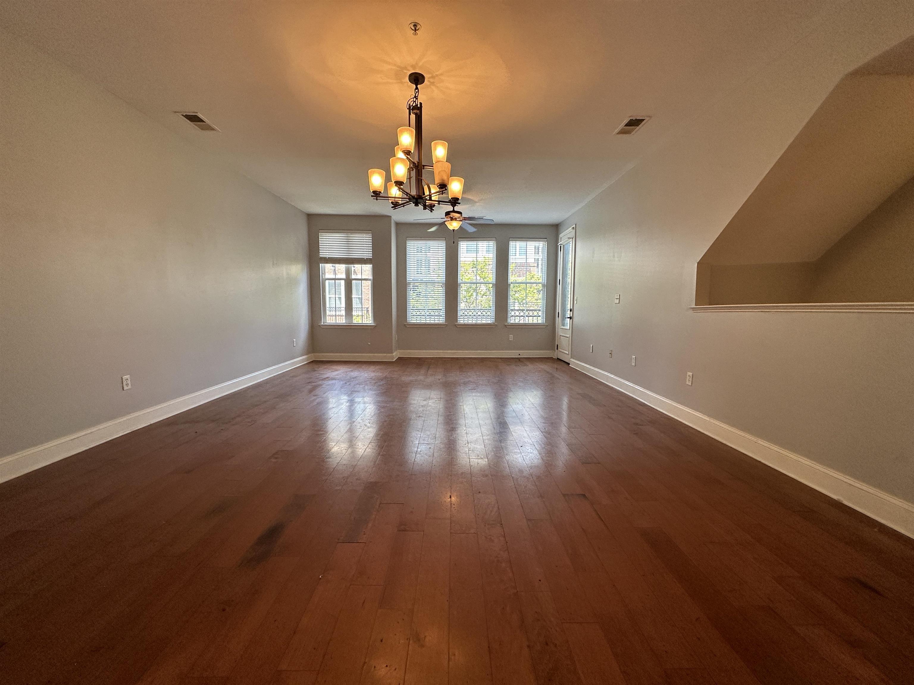 75 Shoemaker Court, Unit 304 Memphis, TN 38103 - Photo 4 of 25 Spare room featuring dark wood-type flooring and an inviting chandelier
