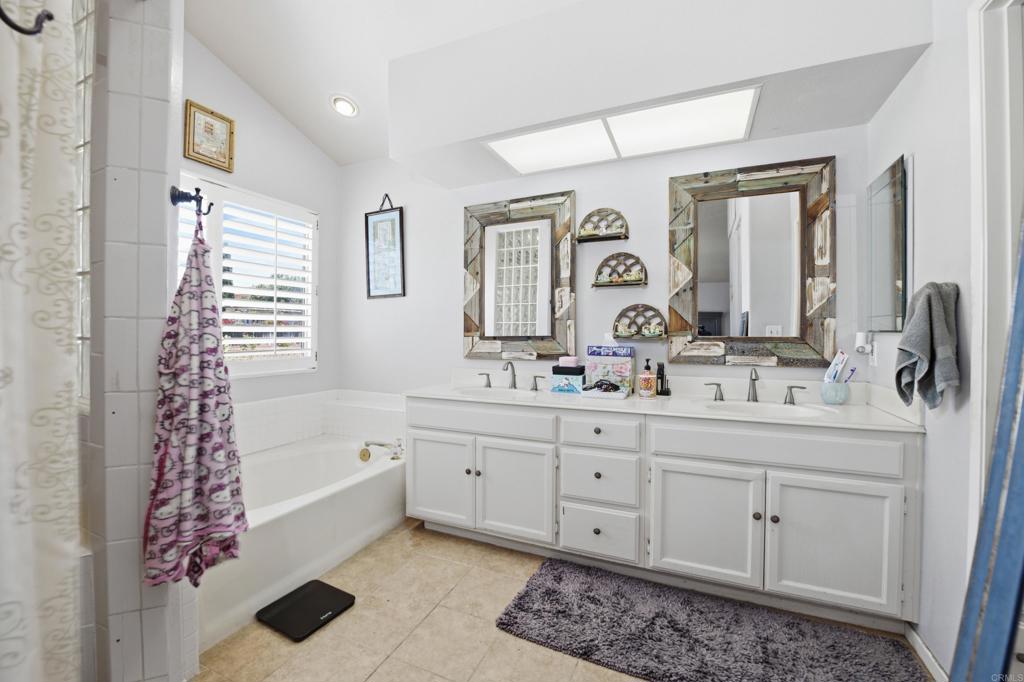 2077 Westwood Road Vista, CA 92083 - Photo 21 of 37 a bathroom with a two sinks a large mirror and a bathtub next to a window
