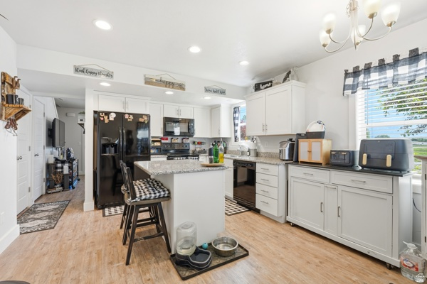 391 South 440th Street West Preston, ID 83263 - Photo 6 of 28 Kitchen featuring white cabinetry, black appliances, recessed lighting, wood-finish flooring, and a central island with a light-toned countertop