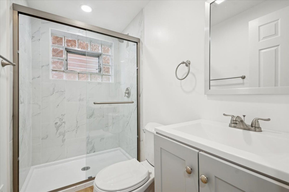 2623 West Arthur Avenue, Unit 1 Chicago, IL 60645 - Photo 10 of 11 a bathroom with a shower sink vanity mirror and toilet