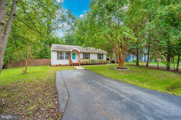 a view of house with a big yard and large trees