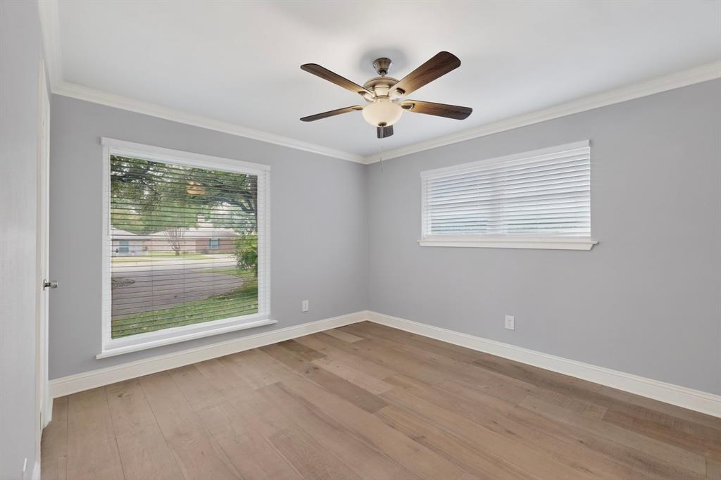 7631 Meadow Road Dallas, TX 75230 - Photo 22 of 40 A bright bedroom with a ceiling fan and wide windows