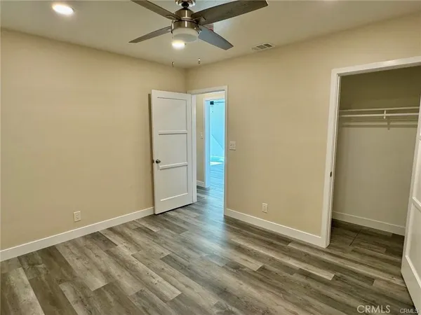 en empty room with wooden floor closet and windows
