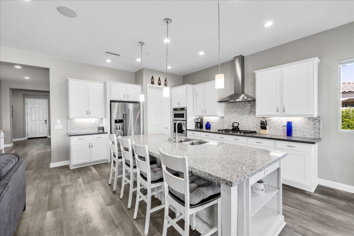 72 Barolo Rancho Mirage, CA 92270 - Photo 29 of 65 a kitchen with stainless steel appliances granite countertop a kitchen island a stove a table and chairs in it