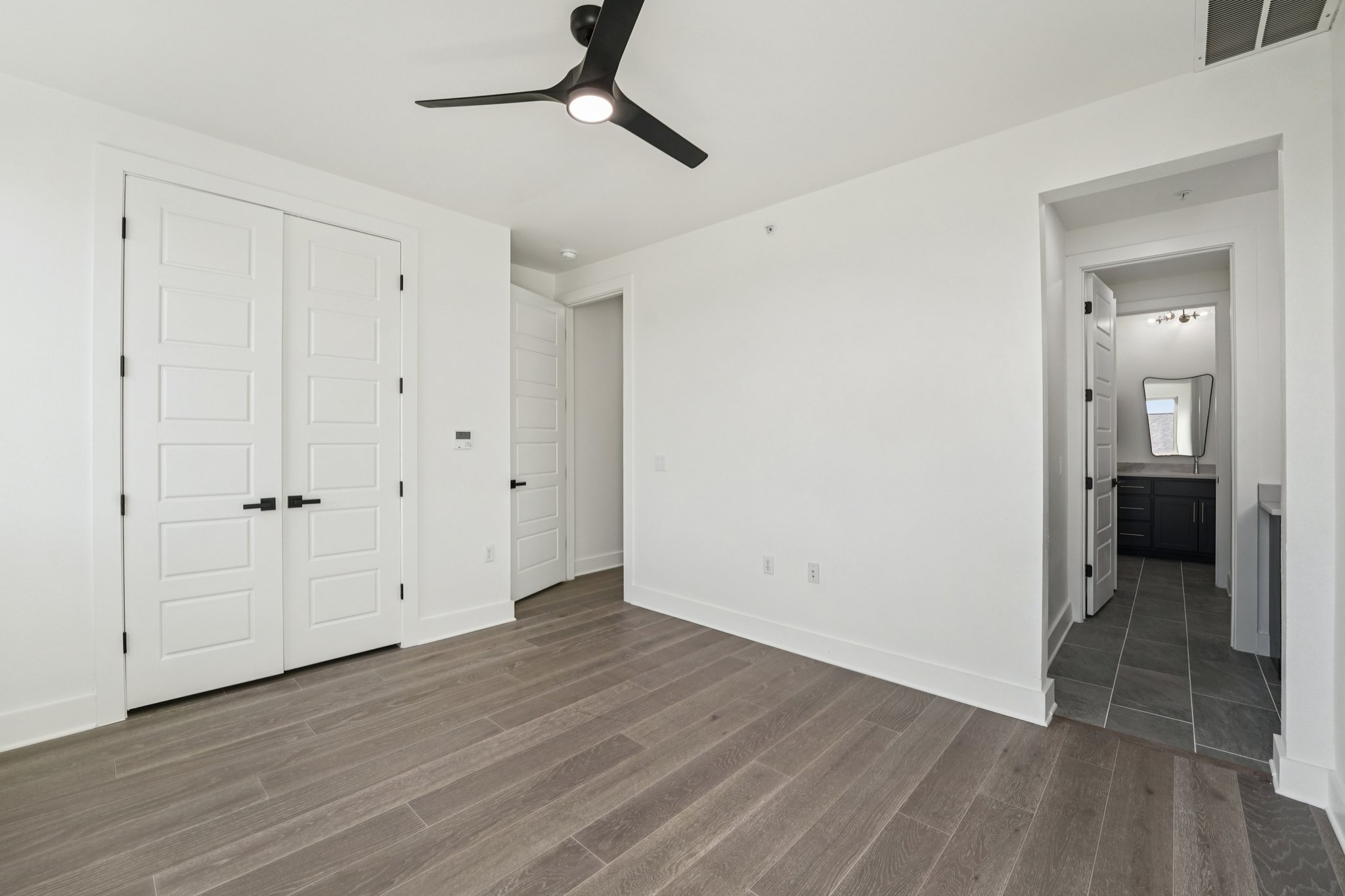 2811 Zach Scott Street Austin, TX 78723 - Photo 28 of 37 Unfurnished bedroom featuring dark wood-style floors, a ceiling fan, ensuite bathroom, and a closet