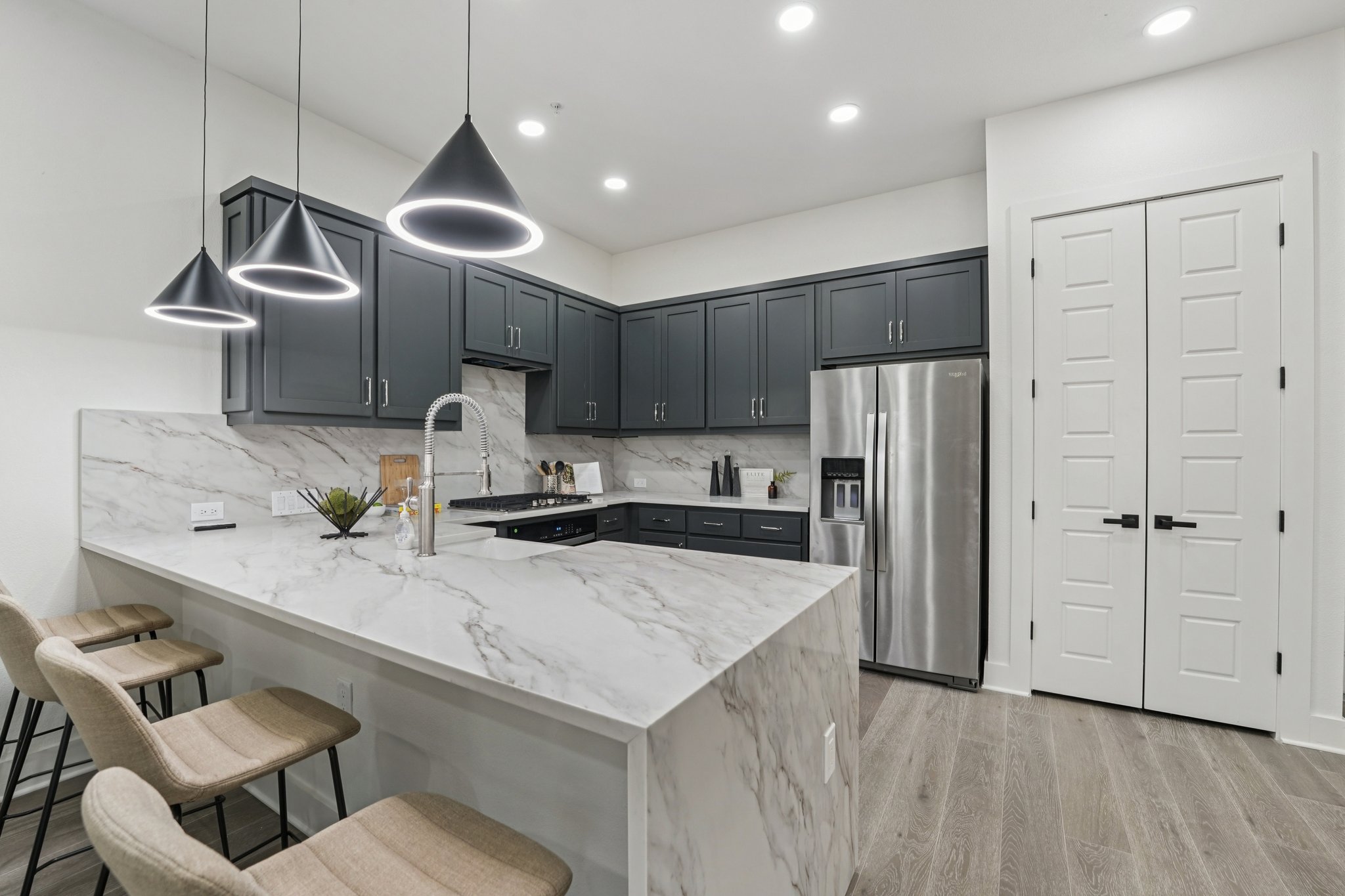 2811 Zach Scott Street Austin, TX 78723 - Photo 9 of 37 Kitchen featuring hanging light fixtures, a peninsula, tasteful backsplash, a kitchen bar, and stainless steel fridge with ice dispenser