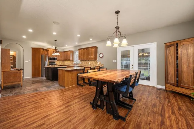 a dining room with stainless steel appliances wooden floors a table and chairs