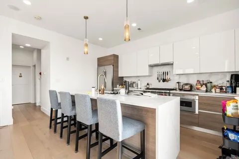 a kitchen with stainless steel appliances a dining table chairs stove and white cabinets