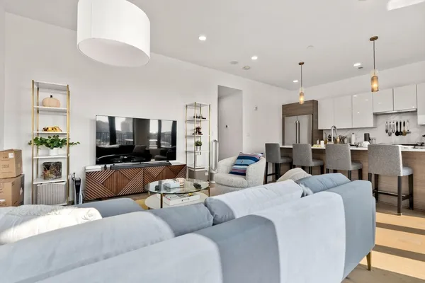 a living room with furniture kitchen view and a flat screen tv