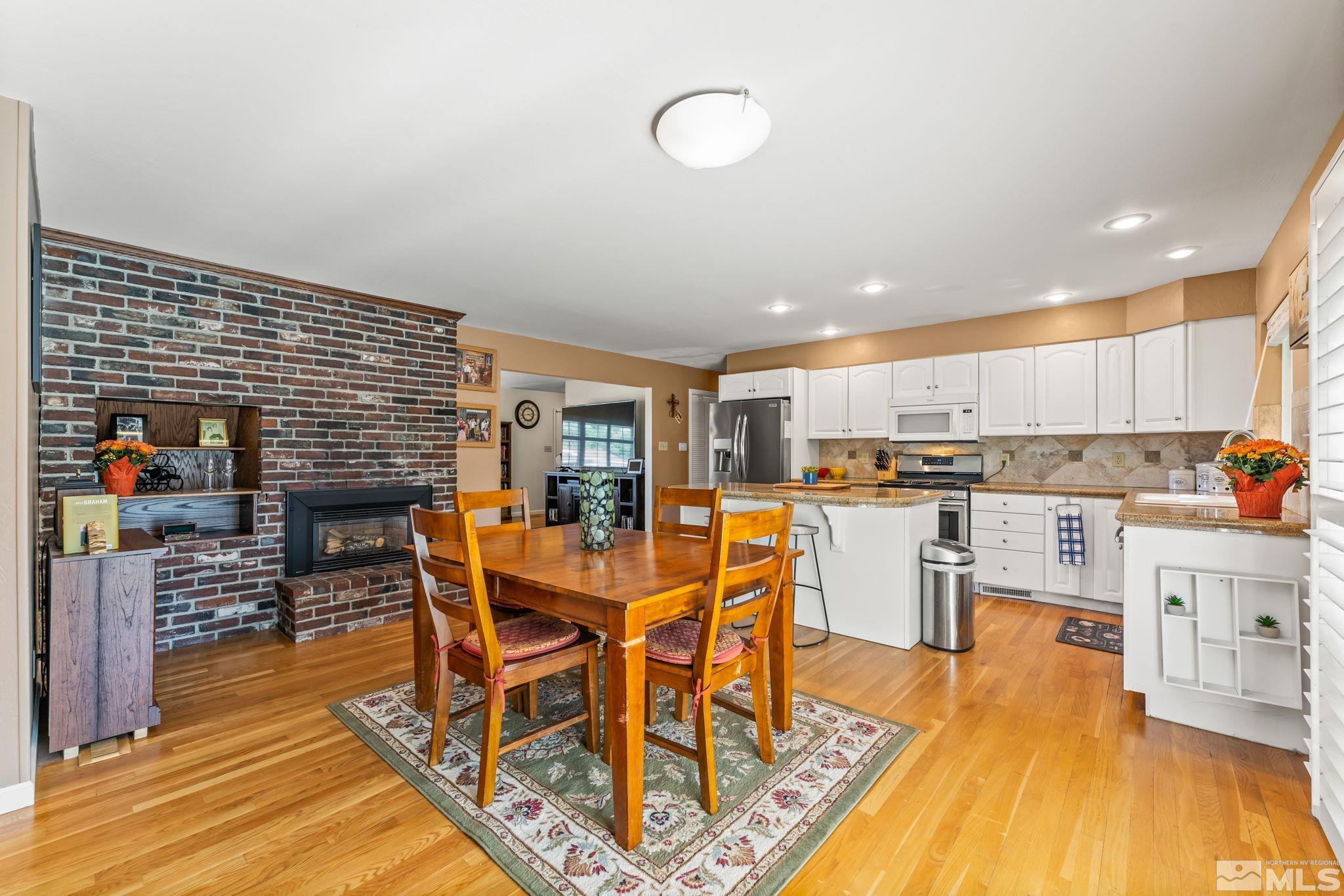 1070 Pineridge Drive Reno, NV 89509 - Photo 11 of 24 a dining room with stainless steel appliances kitchen island granite countertop a table chairs and a refrigerator