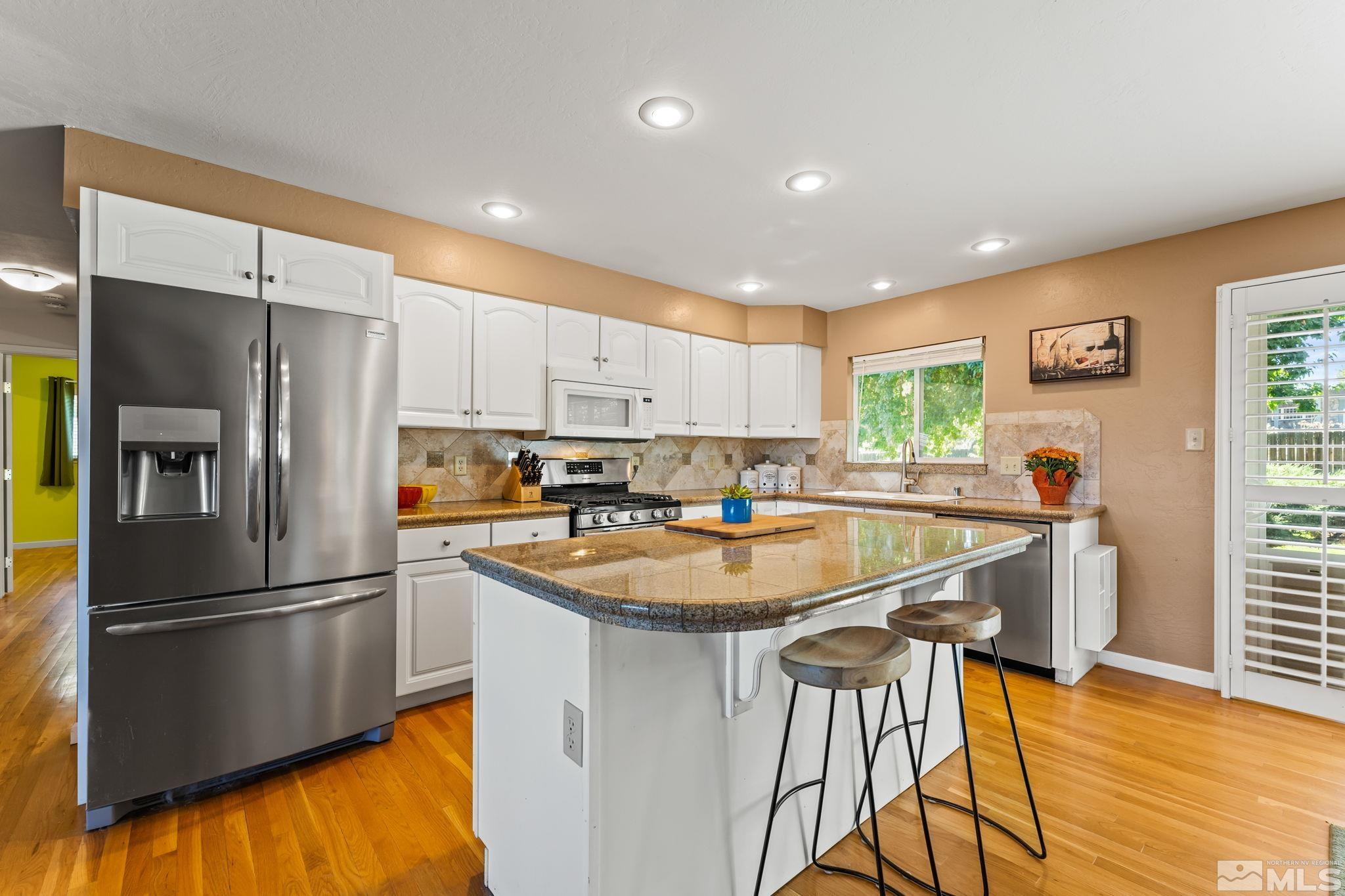 1070 Pineridge Drive Reno, NV 89509 - Photo 8 of 24 a kitchen with stainless steel appliances granite countertop a refrigerator a sink a stove a dining table and chairs with wooden floor