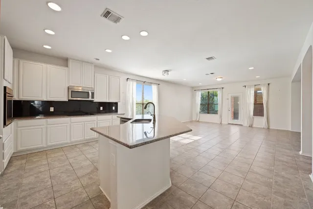 a large white kitchen with kitchen island a sink a stove a microwave and a refrigerator