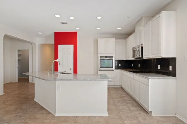 a large white kitchen with stainless steel appliances granite countertop a stove a sink and a refrigerator