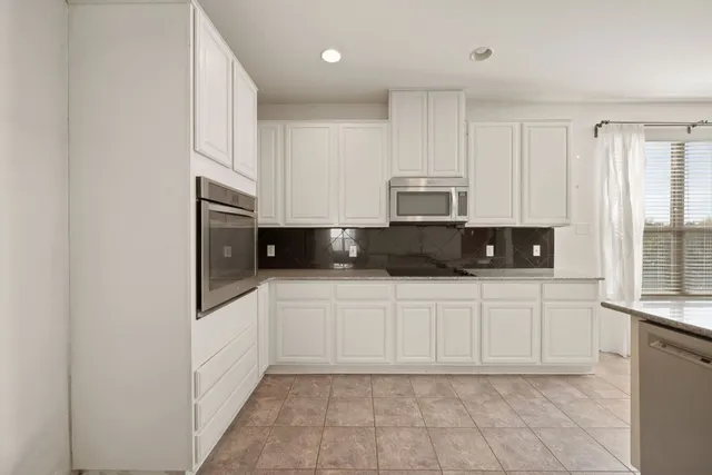 a kitchen with stainless steel appliances a refrigerator sink and white cabinets