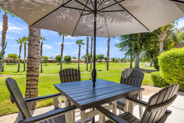 a view of a swimming pool with a table and chairs under an umbrella