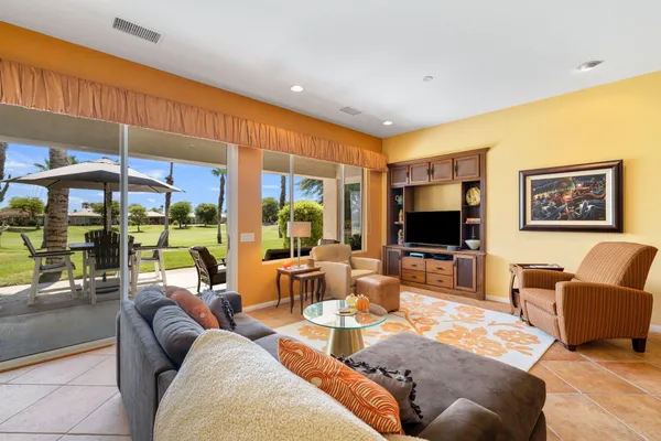 a living room with furniture a flat screen tv and floor to ceiling window