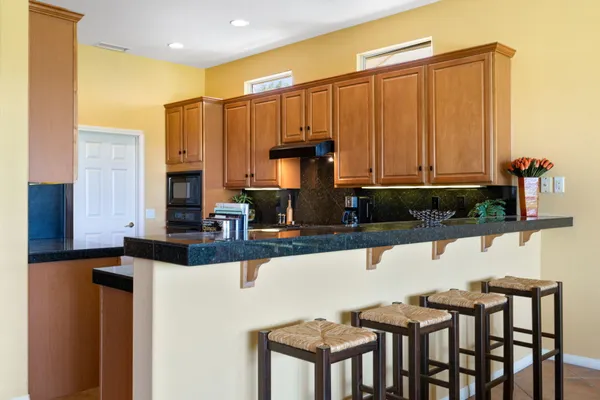a kitchen with granite countertop a stove a sink and a microwave