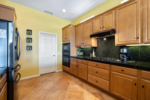a kitchen with granite countertop a refrigerator and cabinets