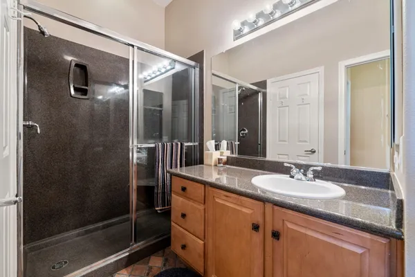 a bathroom with a granite countertop sink a mirror a glass door a shower and vanity