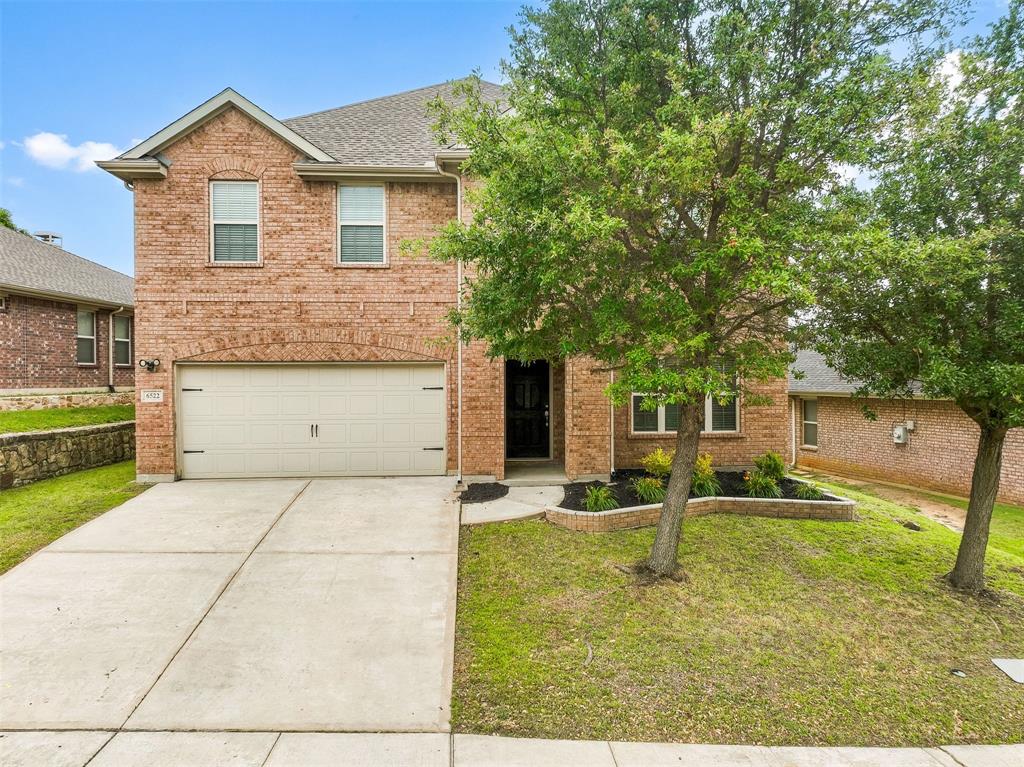 6522 Portside Ridge Lane Dallas, TX 75249 - Photo 2 of 37 Brick exterior featuring a two-car garage, a concrete driveway, and mature front yard trees