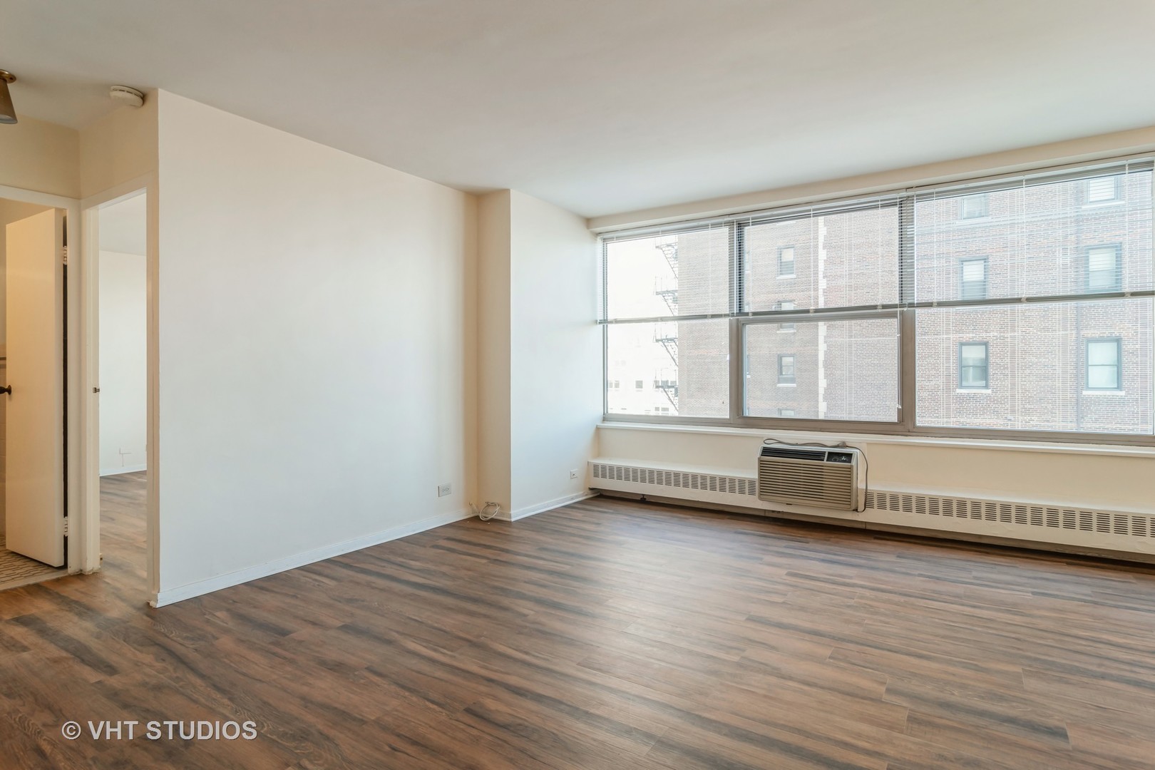 3900 North Lake Shore Drive, Unit 9J Chicago, IL 60613 - Photo 2 of 18 a view of an empty room with wooden floor and a window