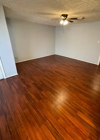 a view of a room with wooden floor a ceiling fan and staircase