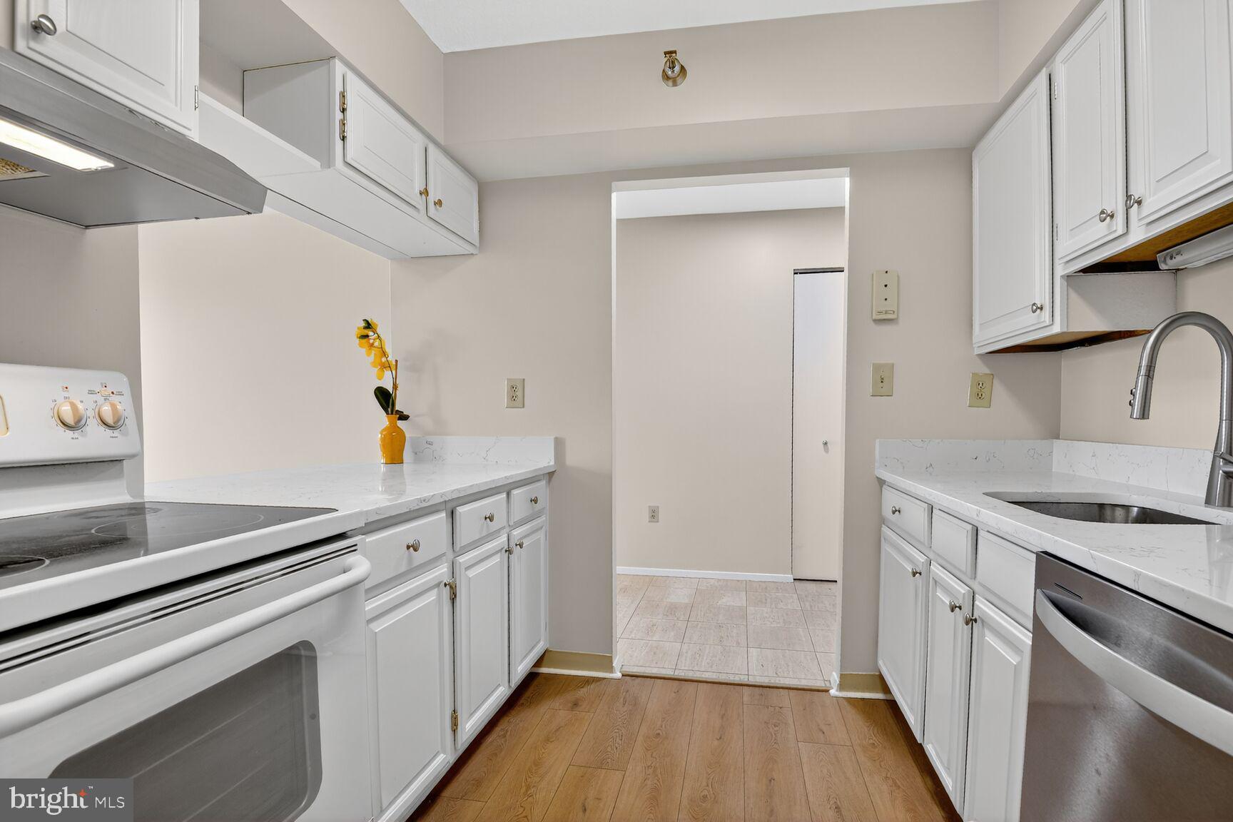 1808 Old Meadow Road, Unit 507 McLean, VA 22102 - Photo 9 of 24 a kitchen with stainless steel appliances a sink dishwasher stove and white cabinets with wooden floor